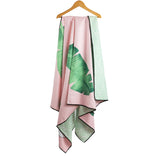 Pale pink towel with bold green leaves hanging on a coat hanger.